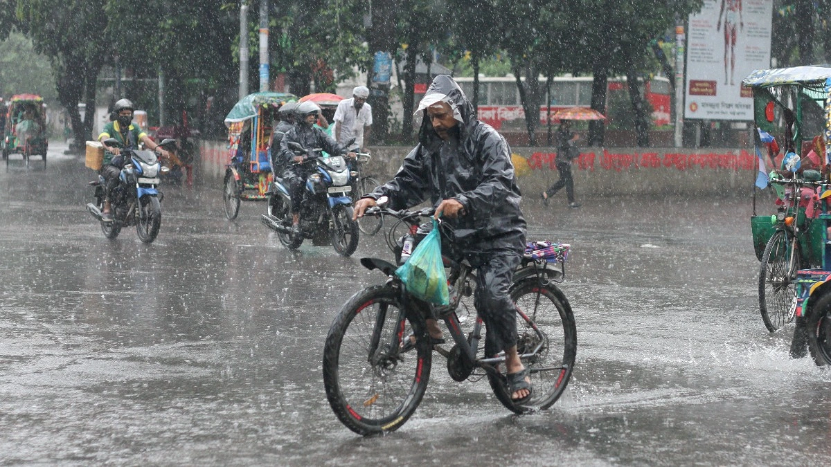 বৃষ্টিতে ভিজে সাইকেল চালিয়ে গন্তব্যে যাচ্ছেন এক ব্যক্তি।