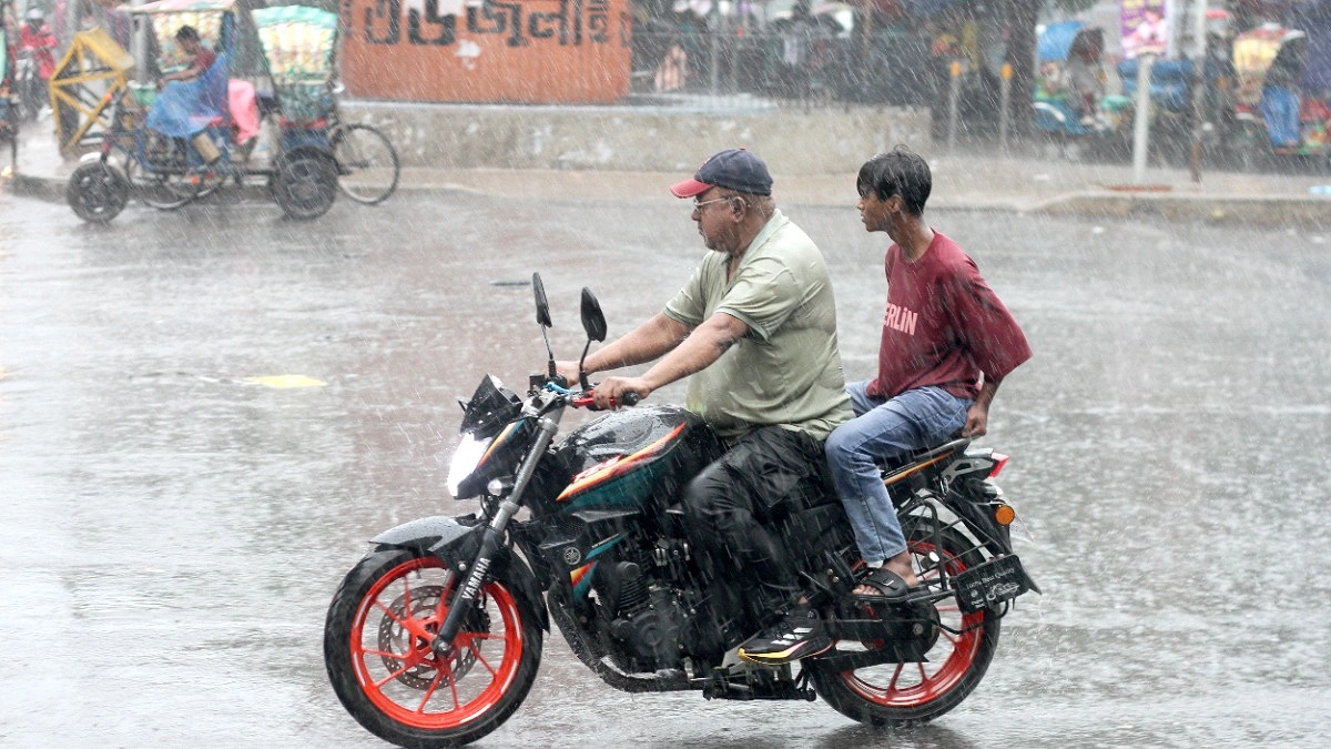 কাকভেজা হয়ে মোটরসাইকেলে গন্তব্যে যাচ্ছেন চালক ও আরোহী।