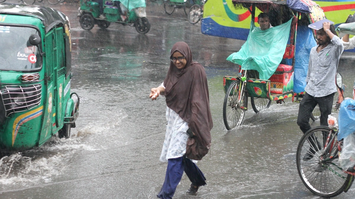 বৃষ্টিতে রাস্তা পার হচ্ছেন এক তরুণী।