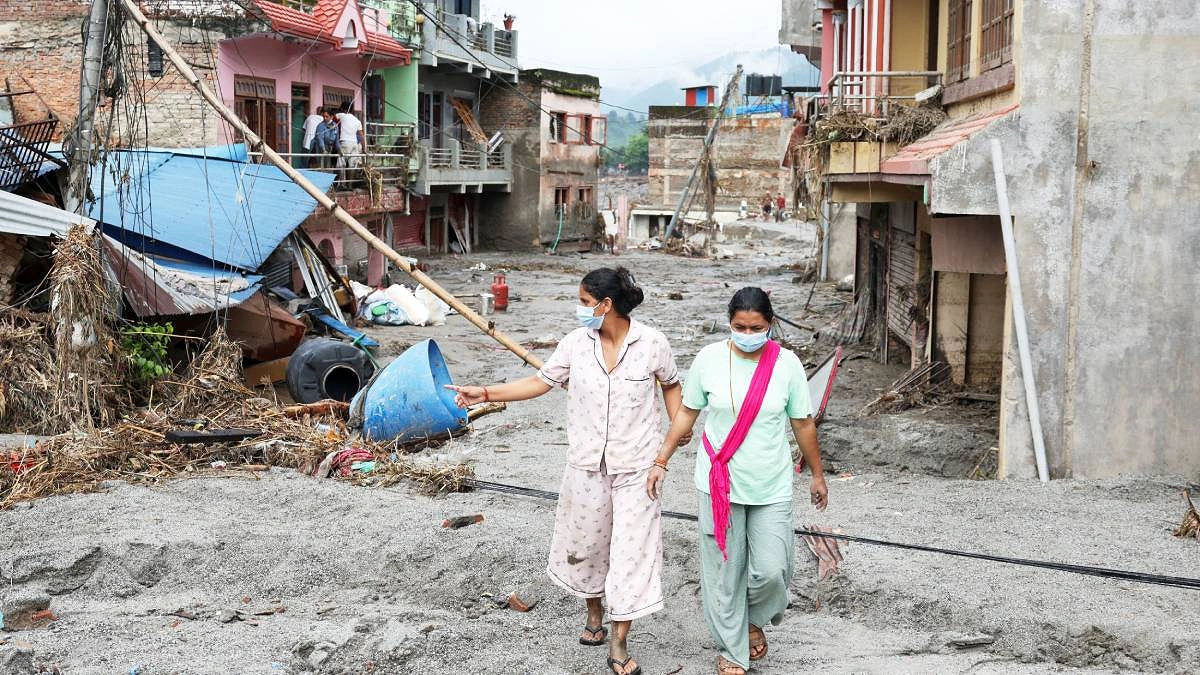 নেপালের নুয়াকোট জেলার দেবীঘাটে বন্যার পর ক্ষতিগ্রস্ত ঘরবাড়ির পাশ দিয়ে হেঁটে যাচ্ছেন নারীরা। ছবি : রয়টার্স