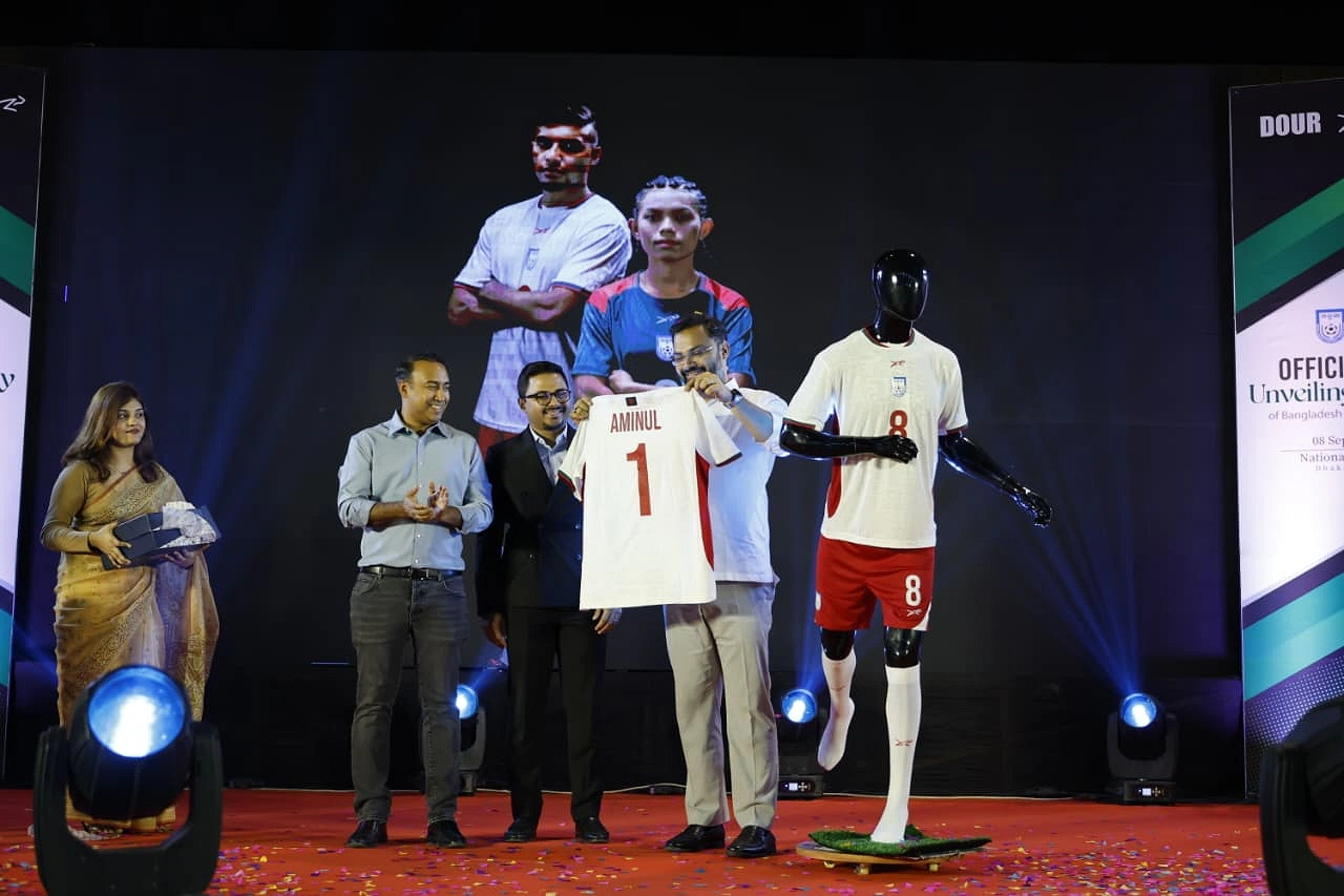 নিজের নাম লেখা জার্সি তুলে ধরছেন ক্রীড়া প্রতিমন্ত্রী আমিনুল হক