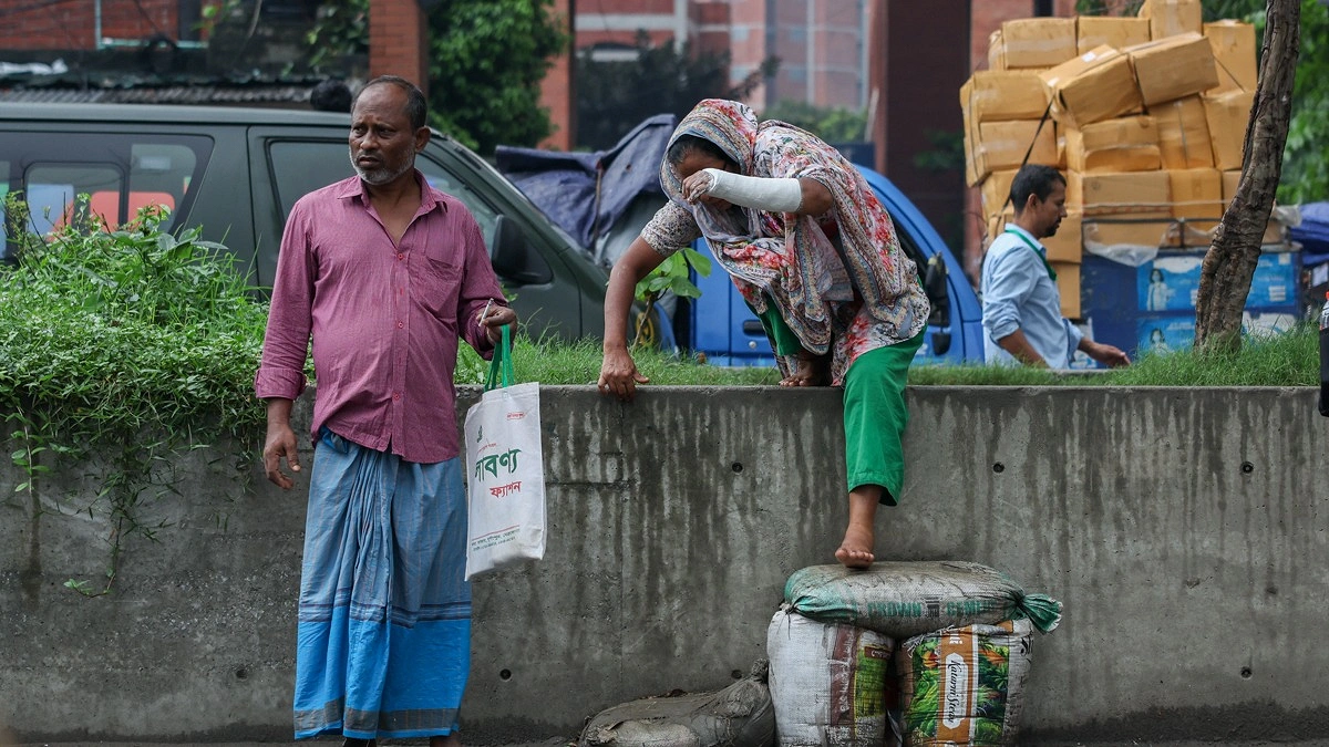 হাতে প্লাস্টার নিয়ে রোড ডিভাইডার থেকে নামছেন একজন নারী