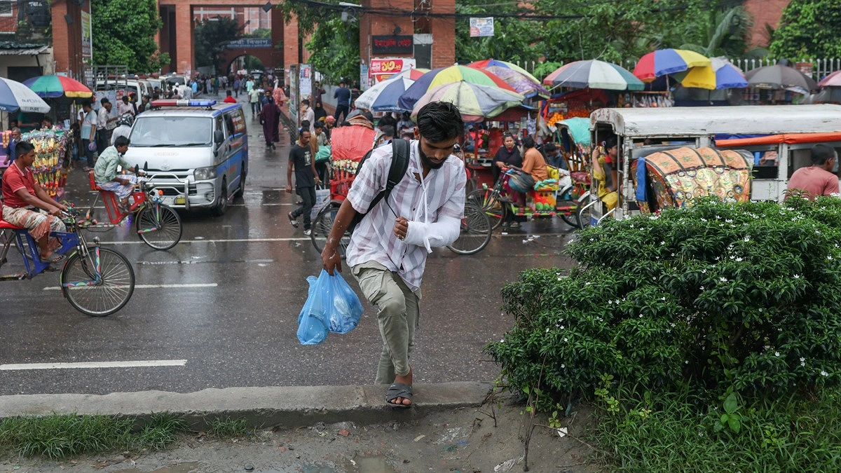 রাস্তা পারাপারের জন্য হাতে প্লাস্টার নিয়েই রোড ডিভাইডারে উঠেছেন একজন।