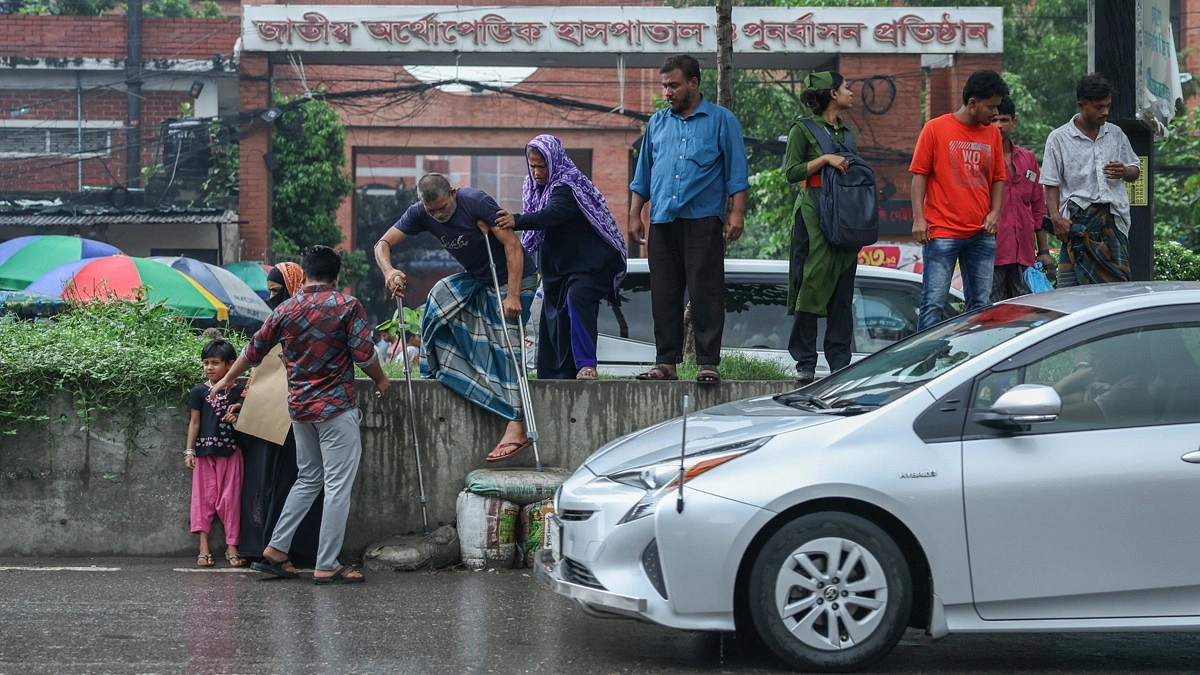 ক্রাচে ভর দিয়ে ব্যস্ত সড়ক পার হতে রোড ডিভাইডার থেকে নামছেন একজন রোগী