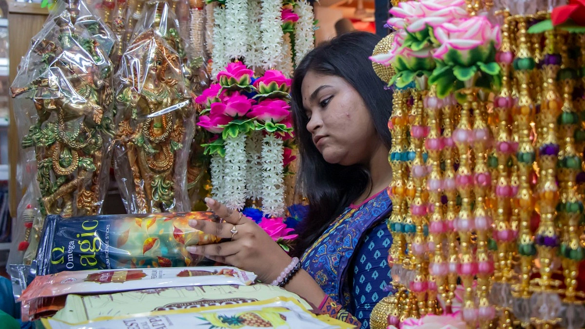 ঘর ও মণ্ডপের সৌন্দর্য বাড়াতে আলো ও সাজসজ্জার জিনিস দেখছেন এক তরুণী।
