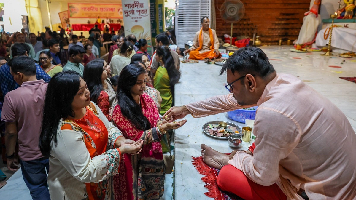 পূজামণ্ডপে ভক্তদের মধ্যে প্রসাদ বিতরণ করা হচ্ছে