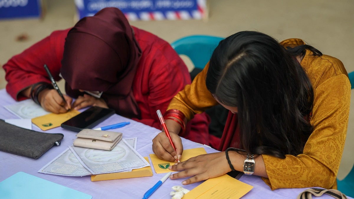 উৎসবে চিঠির খামে ঠিকানা লিখছেন দর্শনার্থীরা