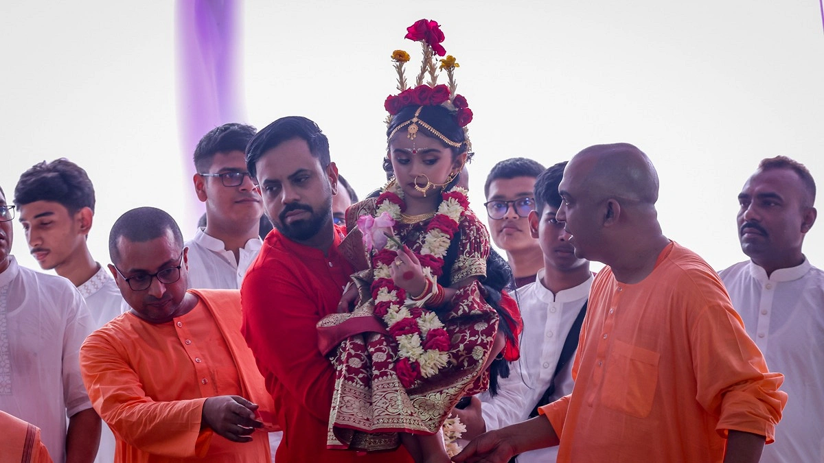কোলে করে কুমারীকে পূজার আসনে নিয়ে আসছেন একজন ভক্ত