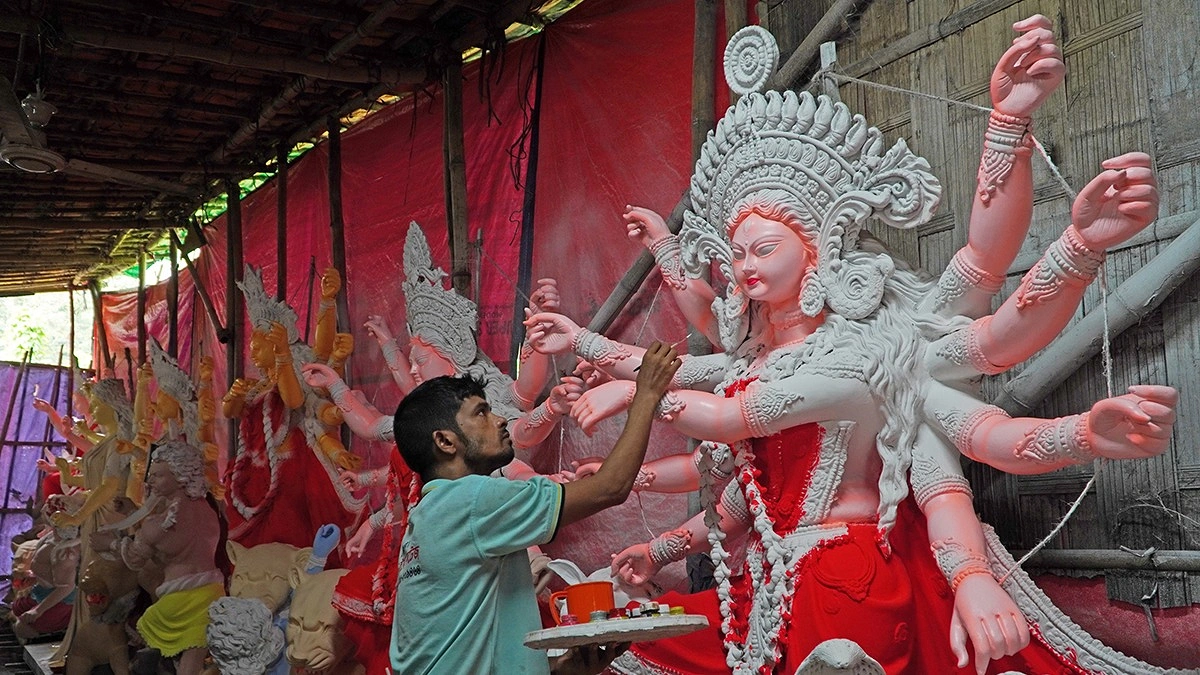 প্রতিমায় শেষ মুহূর্তের রং-তুলির আঁচড় দিচ্ছেন শিল্পী।